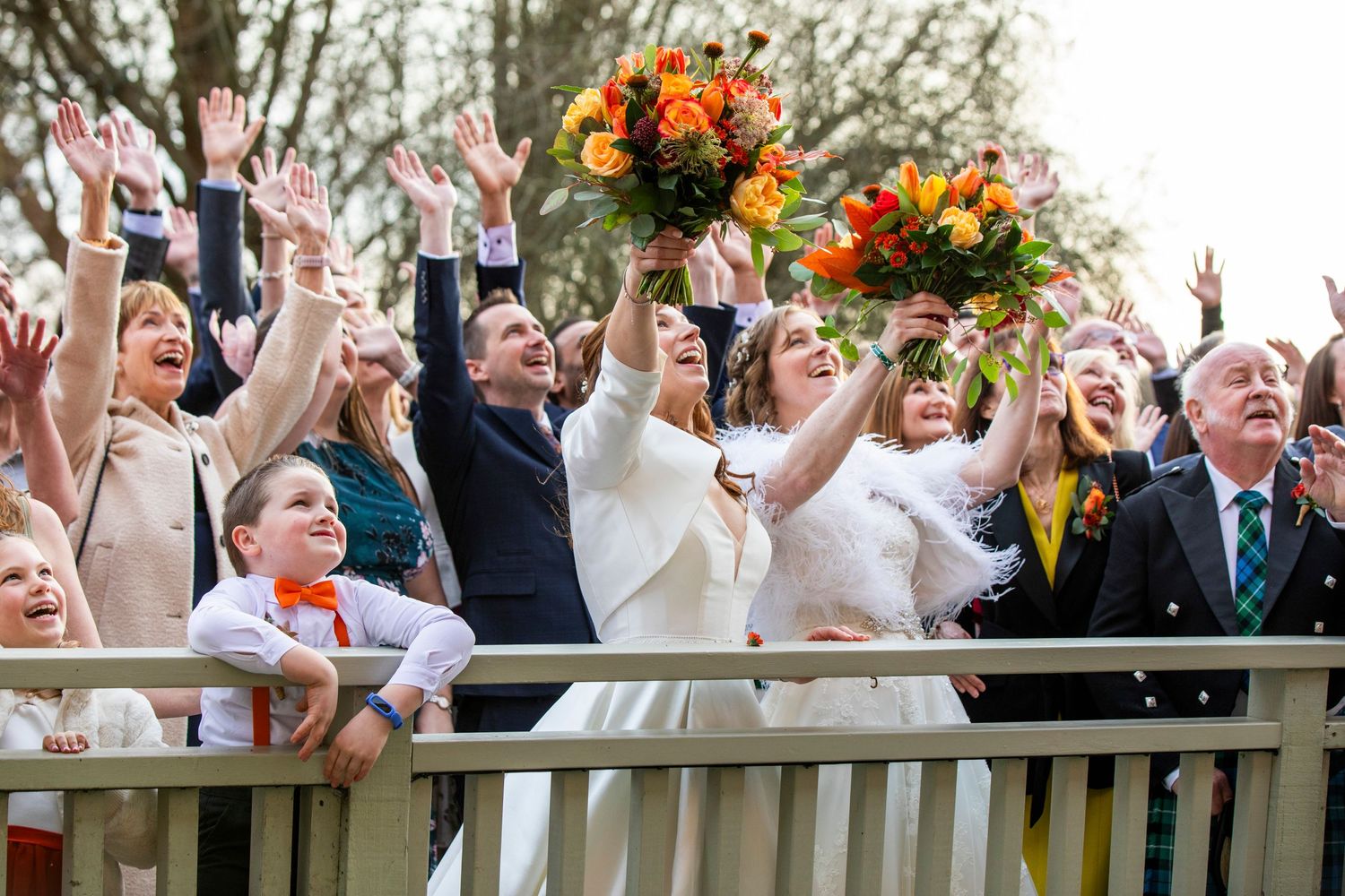 Wedding guests celebrating with raised hands during outdoor reception.