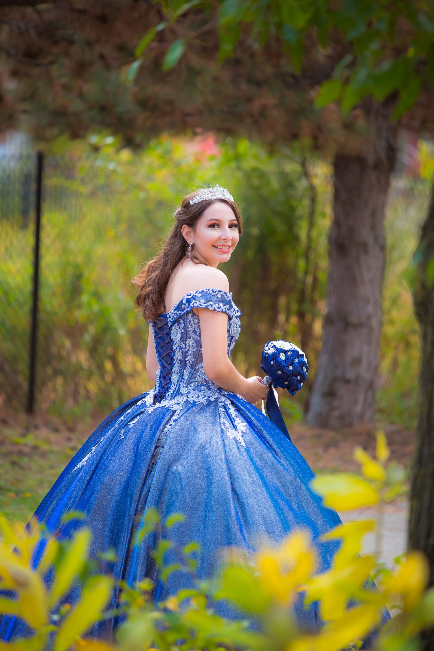 Enchanting garden photo of a sparkling blue quinceañera dress among yellow flowers.