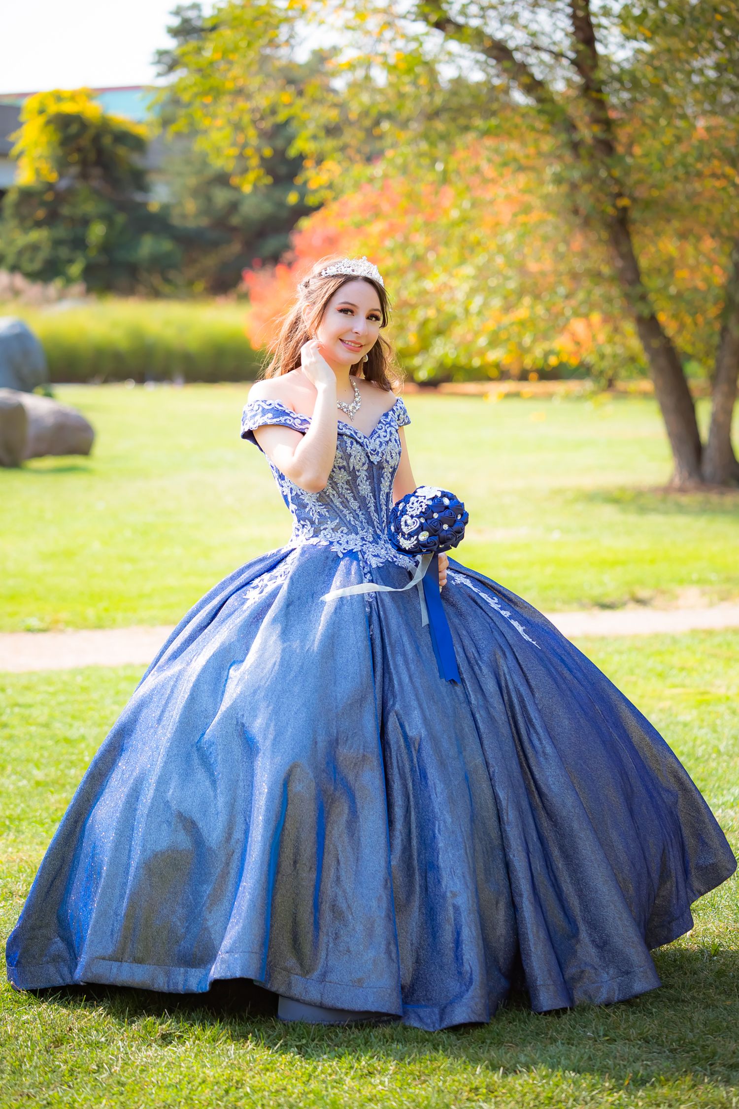 Beautiful portrait of woman in blue princess ball gown against autumn foliage.