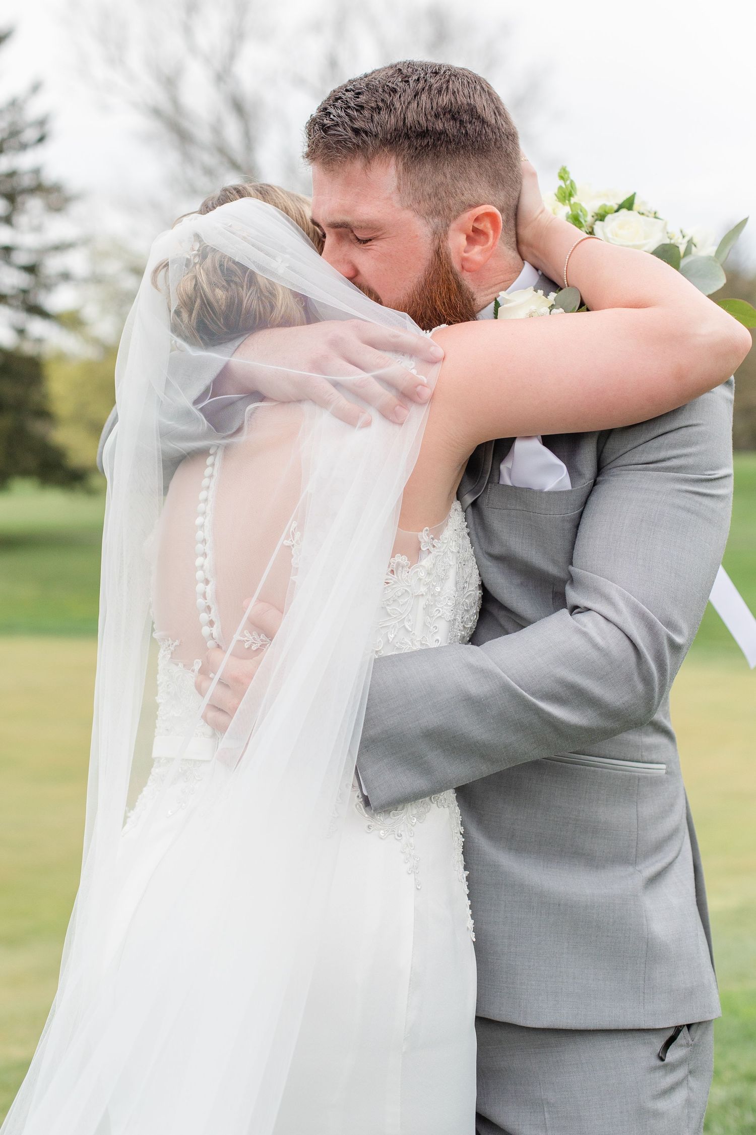 A tender moment between newlyweds embracing outdoors on their wedding day.