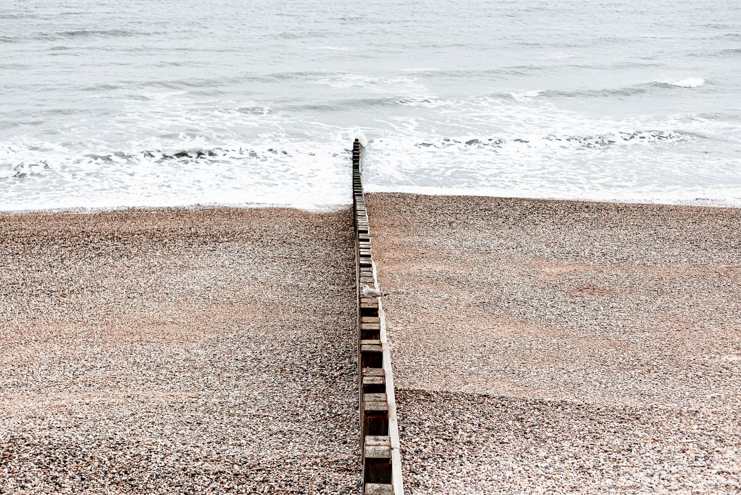 beach with beach wall running through into calm sea. location based airbnb hotspot photography