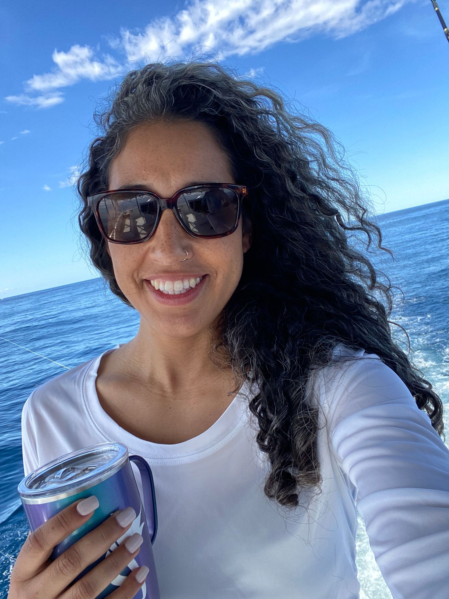 A selfie of Rachel Cuesta wearing a Reel Girl Fishing shirt and a mug on Horse Sportsfishing Charter.