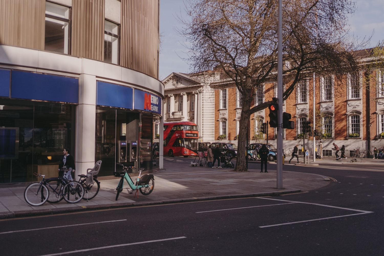 Urban street scene with red double decker bus, bicycles, and brick buildings in London.