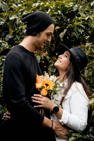 Couple in casual winter wear sharing intimate moment among garden foliage.
