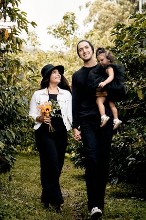 Family walking together through an autumn orchard holding flowers.