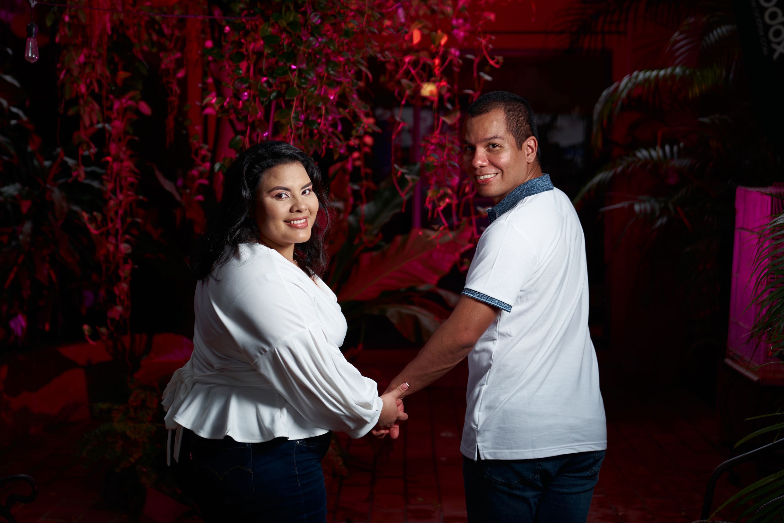 Couple dancing together against dramatic red floral backdrop.