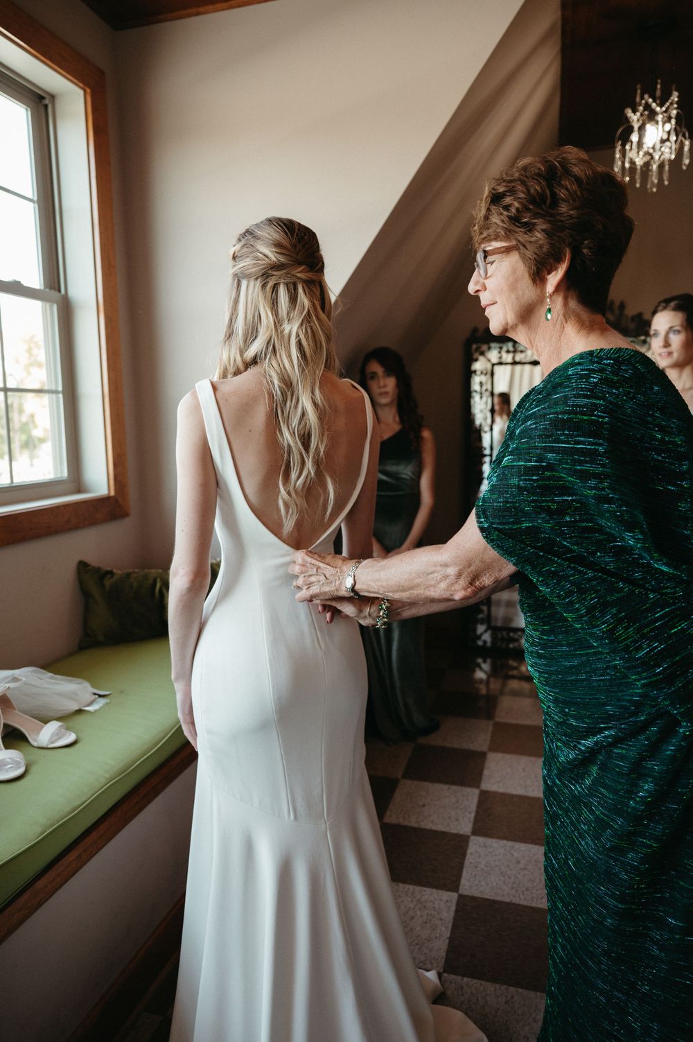 Wedding dress fitting moment showing elegant backless gown in natural window light.