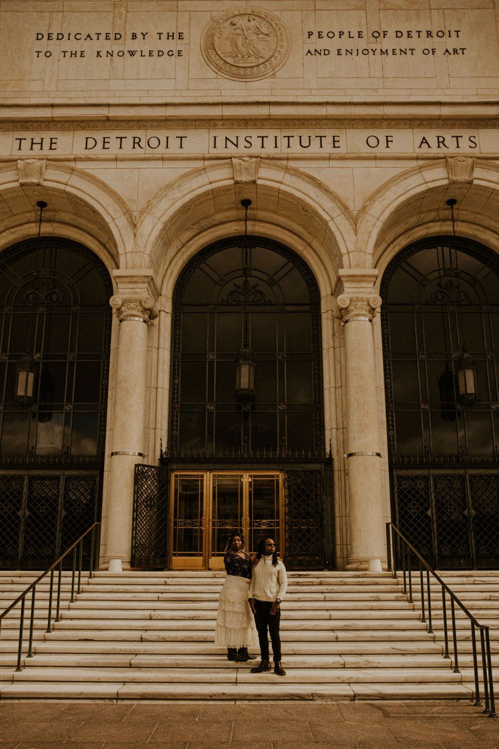 Engagement session in Detroit, Michigan. Couple stands in front of Detroit Institute of Arts.
