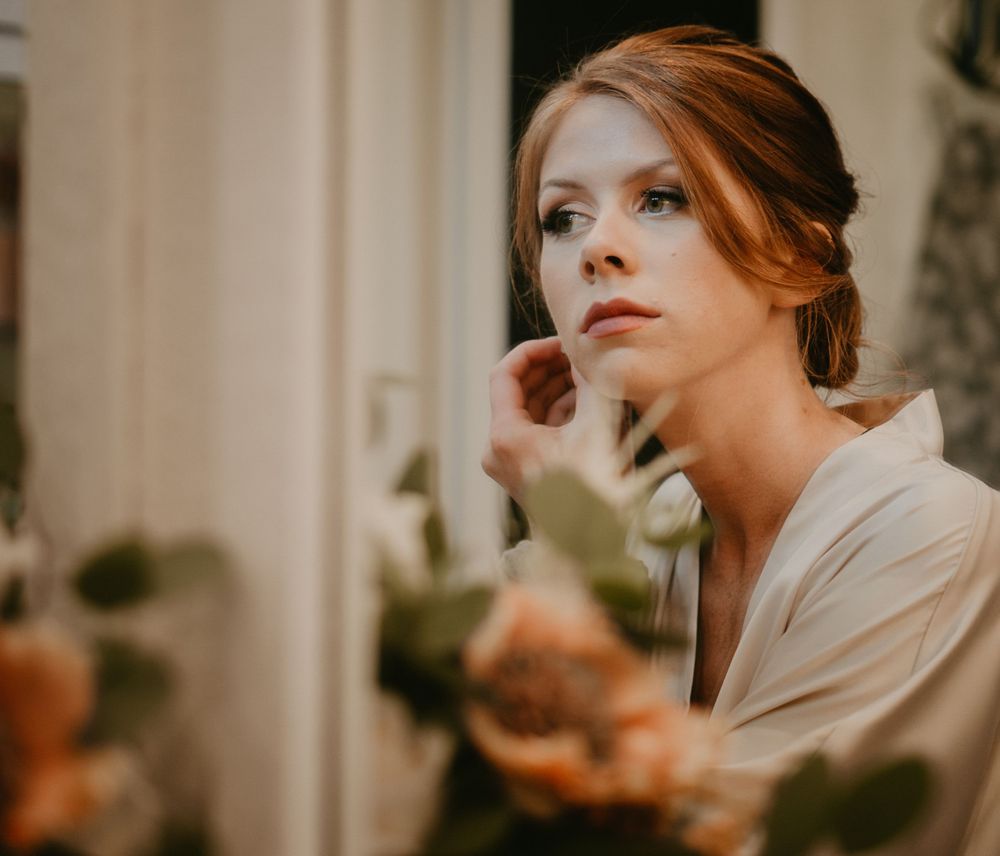 bride behind the scences bride getting ready looking in the mirror putting on earring