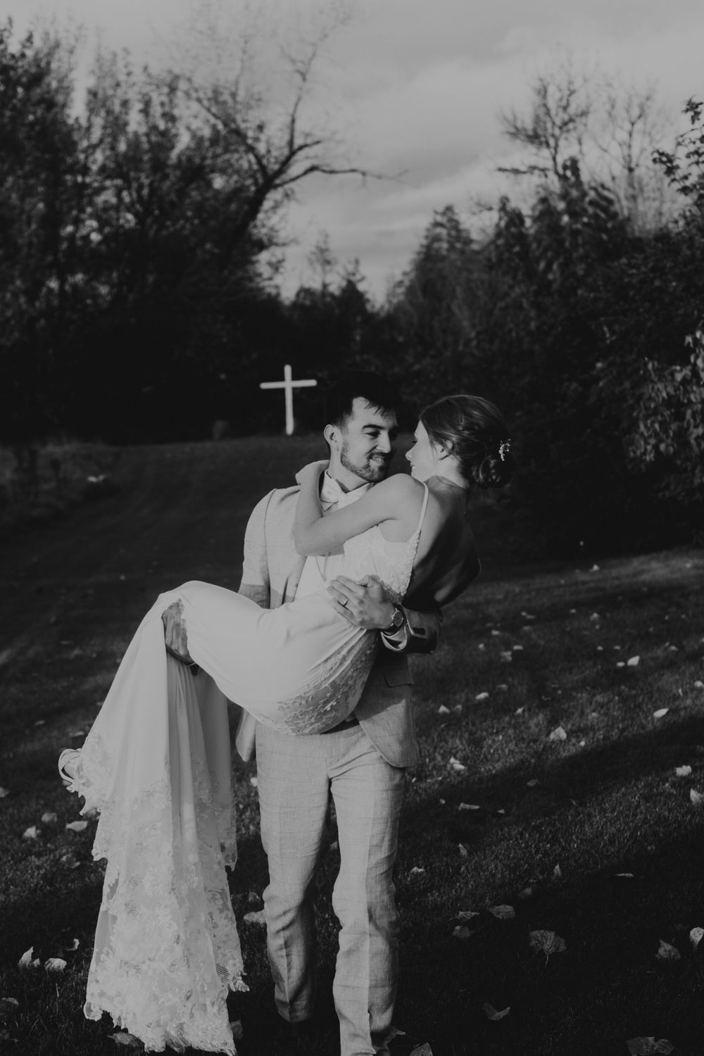 black and white photo bride and groom wedding groom carries bride across the grass