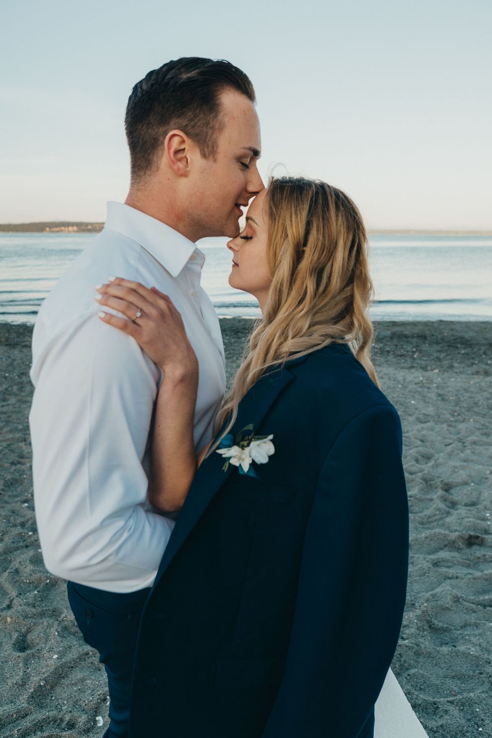 bride and groom beach wedding elopement bride wears grooms suit jacket with boutonniere