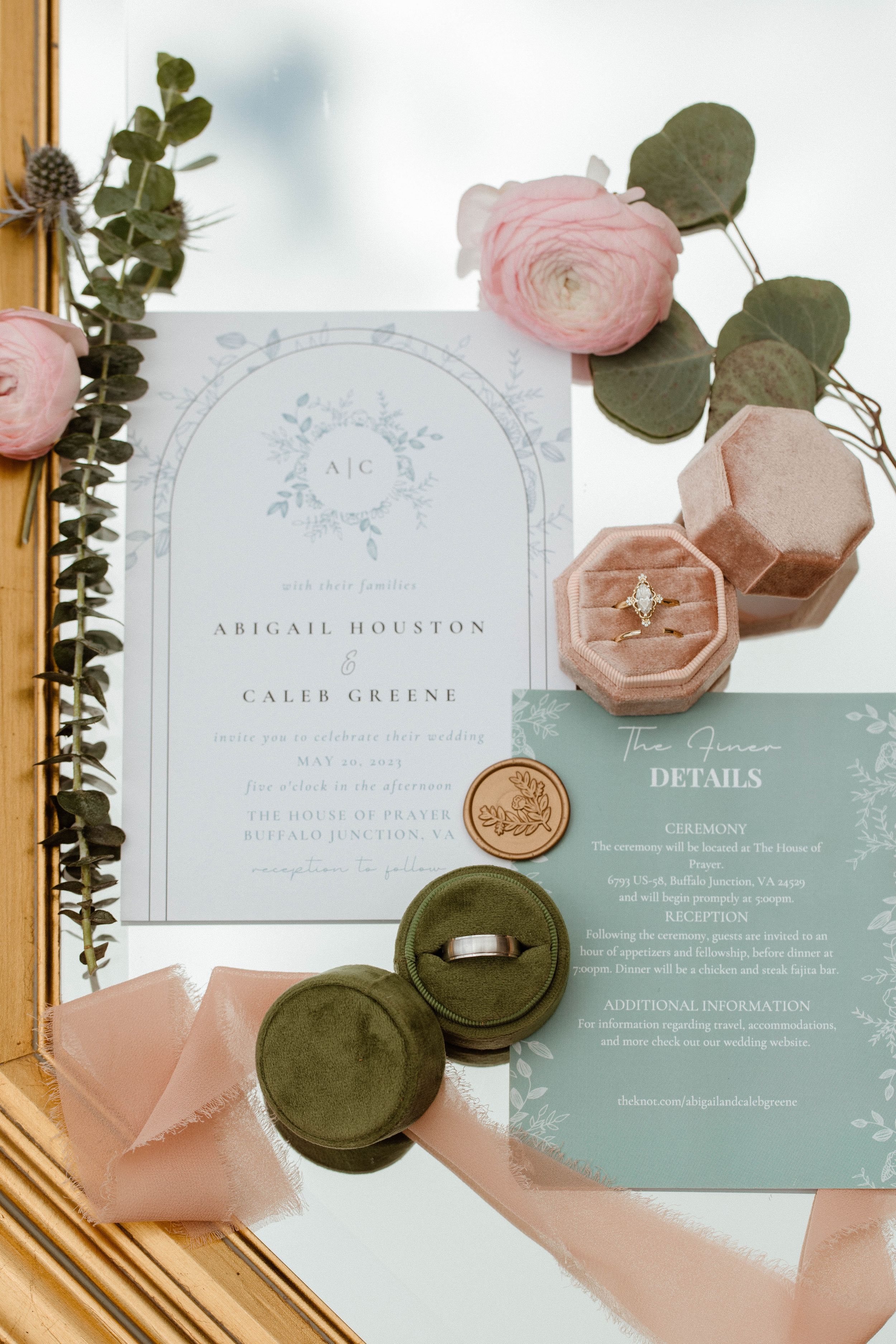 Elegant wedding invitations in soft blue and pink tones with floral accents and gold details.