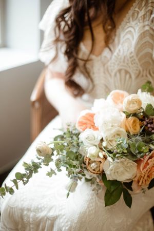 White lace wedding dress adorned with peach and cream floral arrangements.