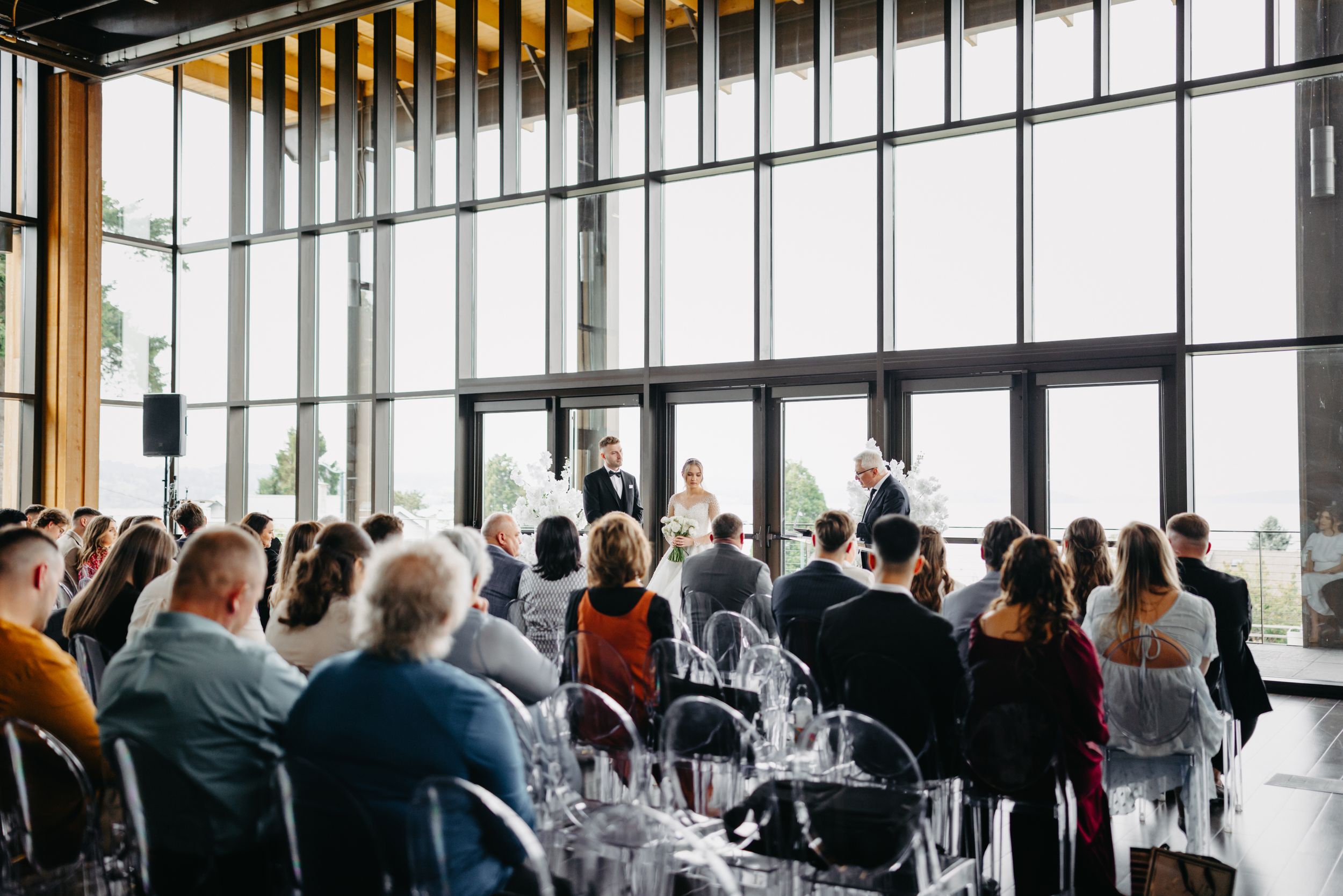 Guests seated at round tables in a modern venue with dramatic floor-to-ceiling windows.