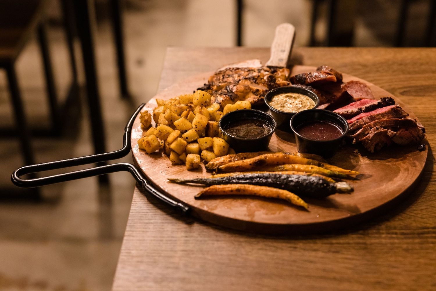 Wooden serving board with various foods and sauces arranged on it.