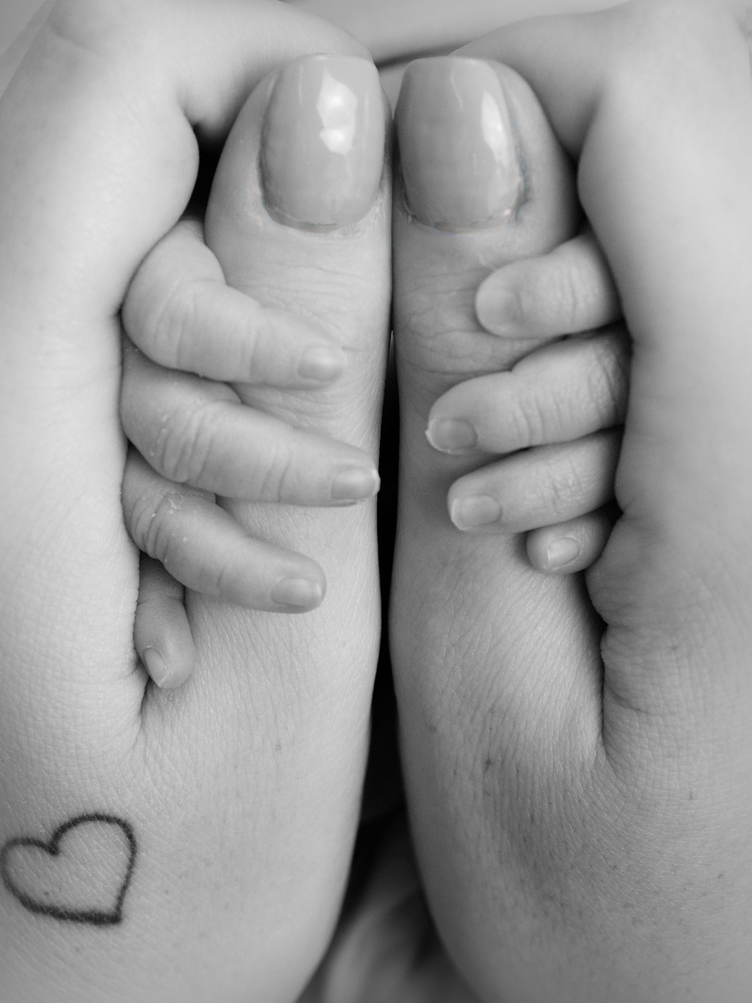 Newborn baby holding on mothers numbs in black and white
