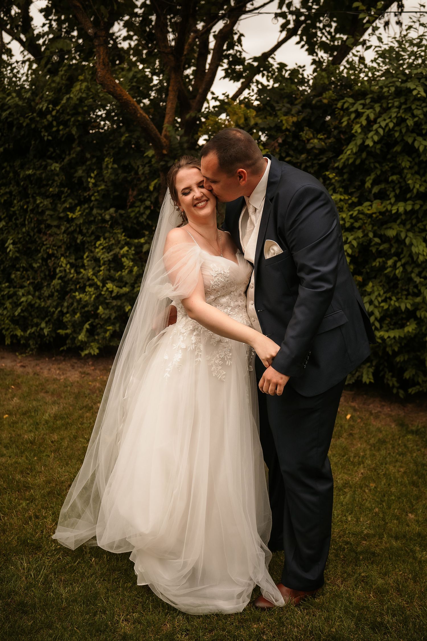 Newlyweds share an intimate laugh together in a lush garden setting.