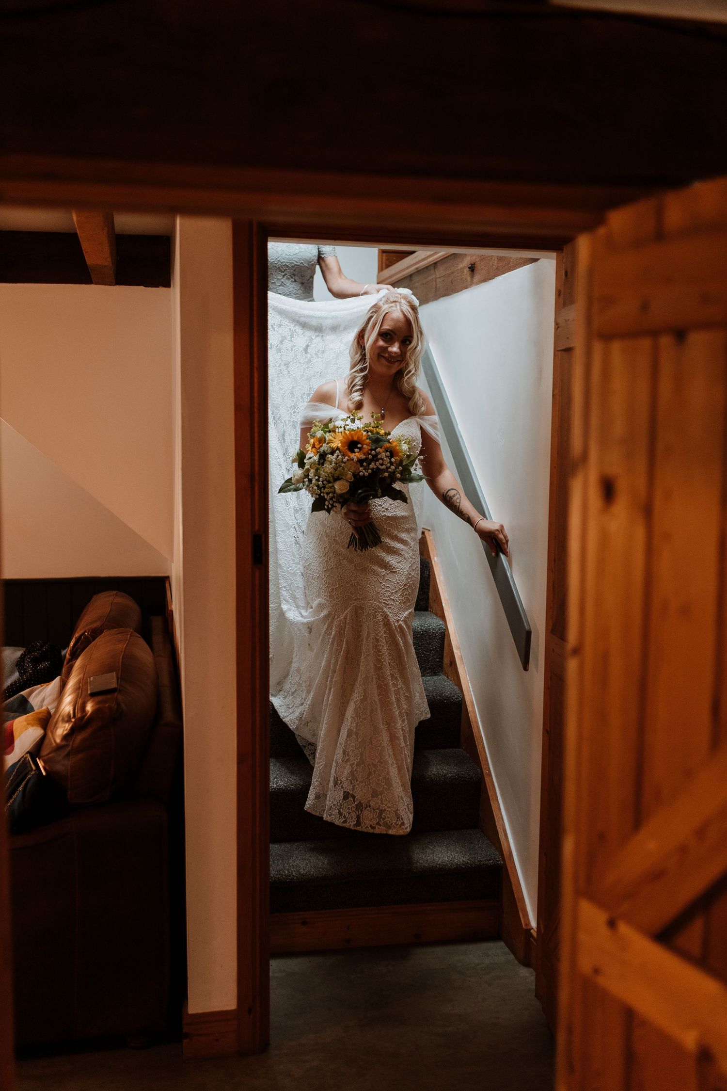 Bride coming down stairs for first look with bridesmaids at Glyngynwydd Wedding Barns, Llanidloes