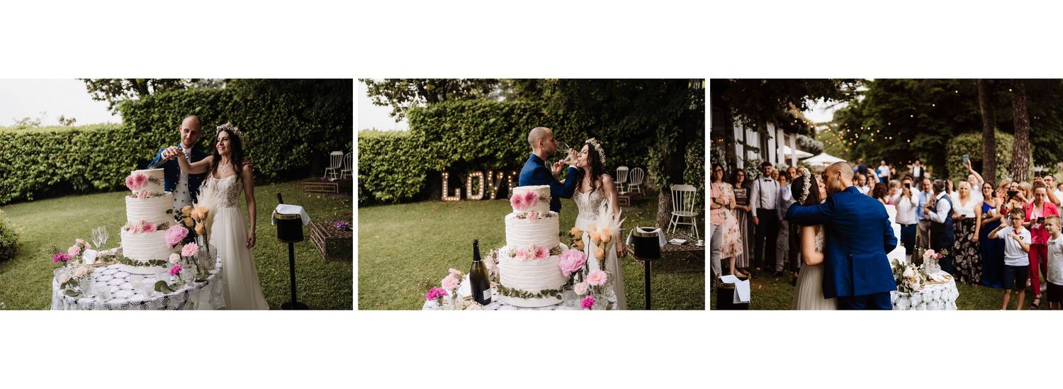 Bride and groom cutting their elegant floral wedding cake outdoors with LOVE letters in background.
