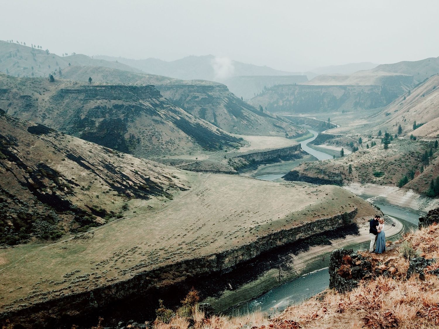 Panoramic view of a winding river valley through mountainous terrain.