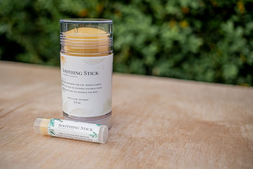 Natural soothing stick balm product displayed outdoors against blurred green background.