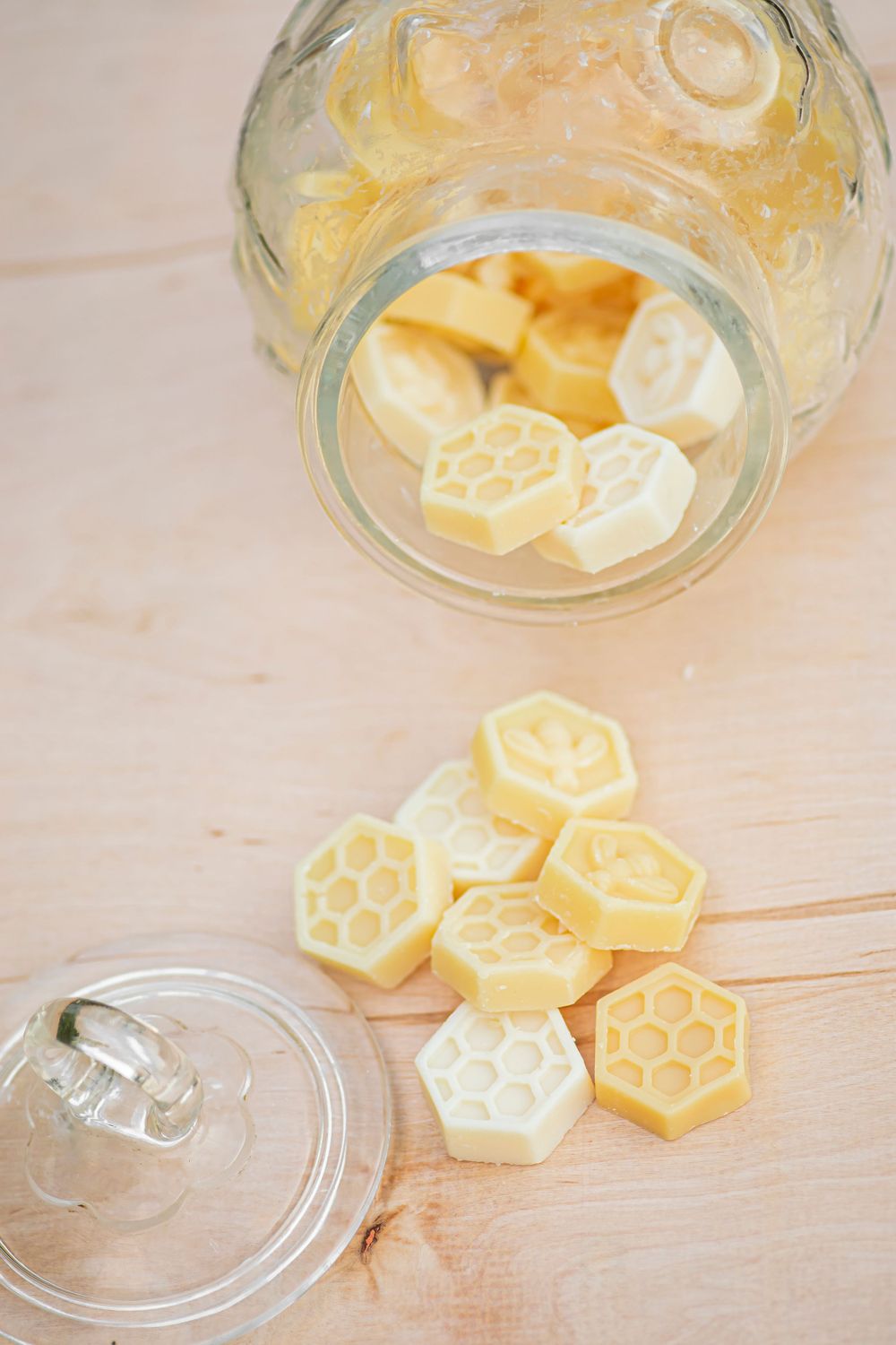 Hexagonal honey-colored bath melts arranged artistically in and around clear glass jar.