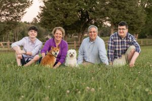 Family sitting in grass with their two dogs on a sunny day.