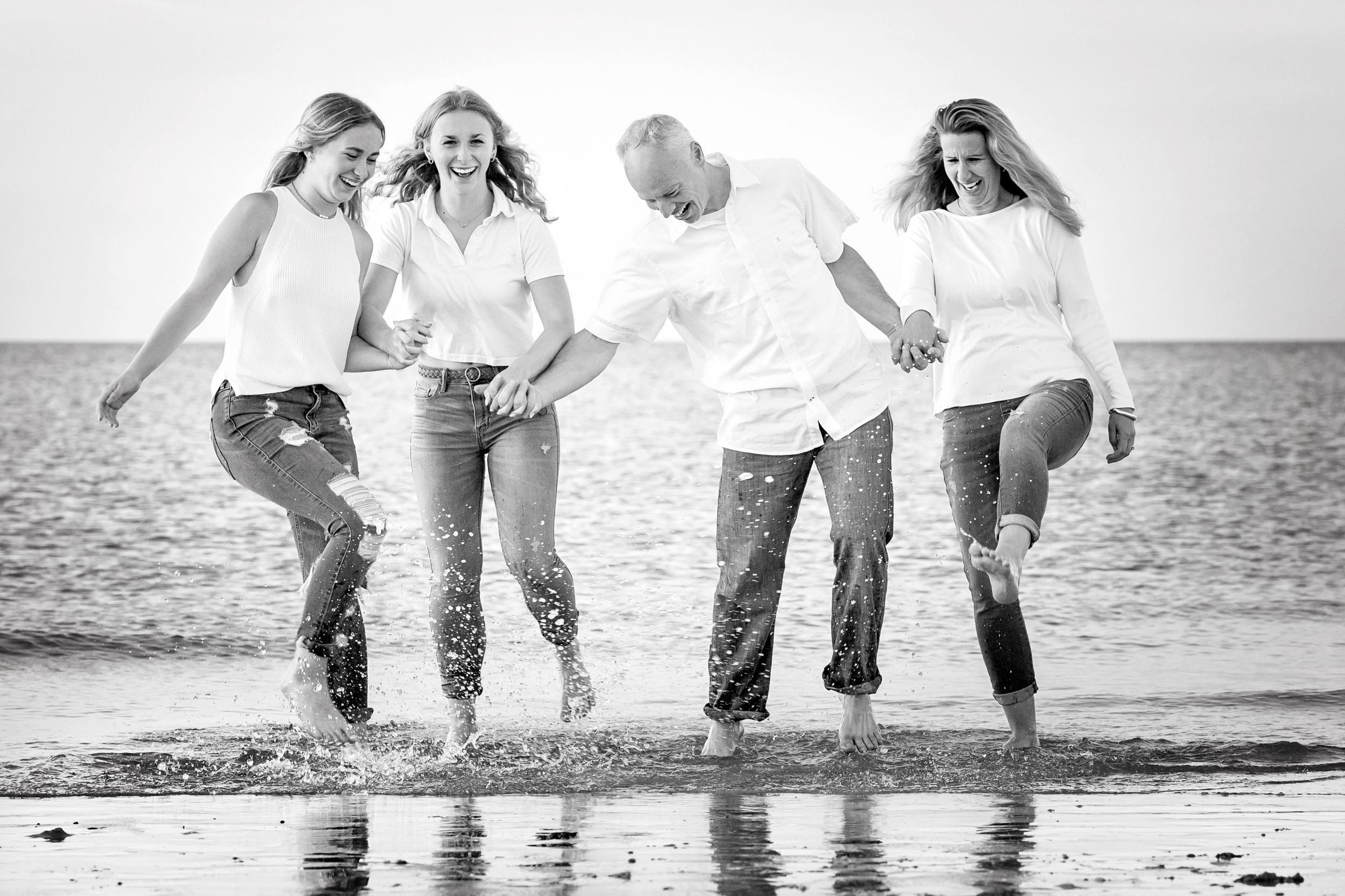 Black and white photo of group splashing and playing in ocean waves at beach.