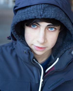 Portrait sequence featuring striking blue eyes peeking out from under a navy blue hooded jacket.