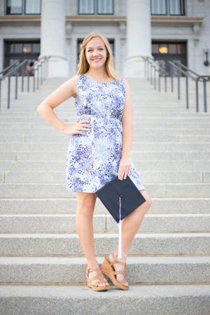 Portrait series on concrete steps wearing a blue and white floral top and navy shorts.