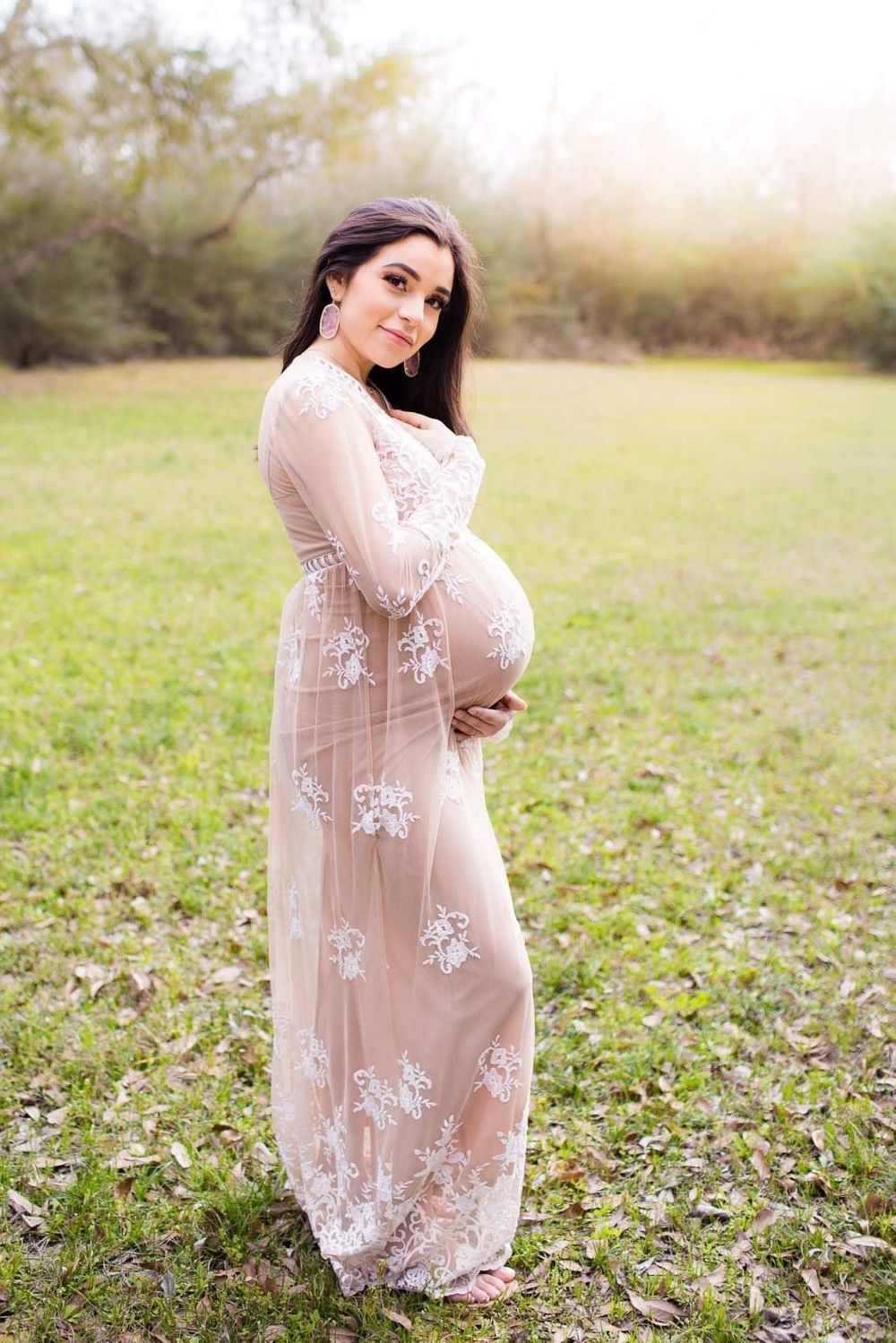 Pregnant mama glowing in white gown while holding belly in Alvin tx and surrounding areas