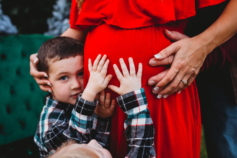Pregnant mom holding belly while siblings and dads hands are on her belly in Alvin Tx
