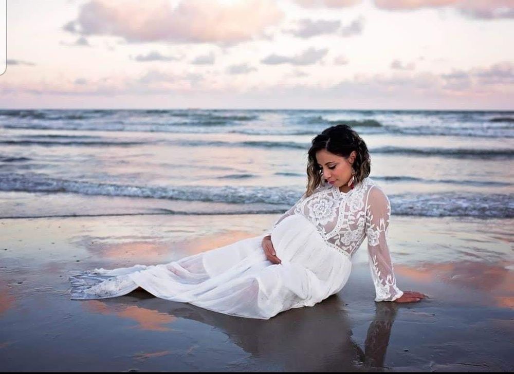 Pregnant mama laying on the beach near the water in Galveston, Tx holding belly