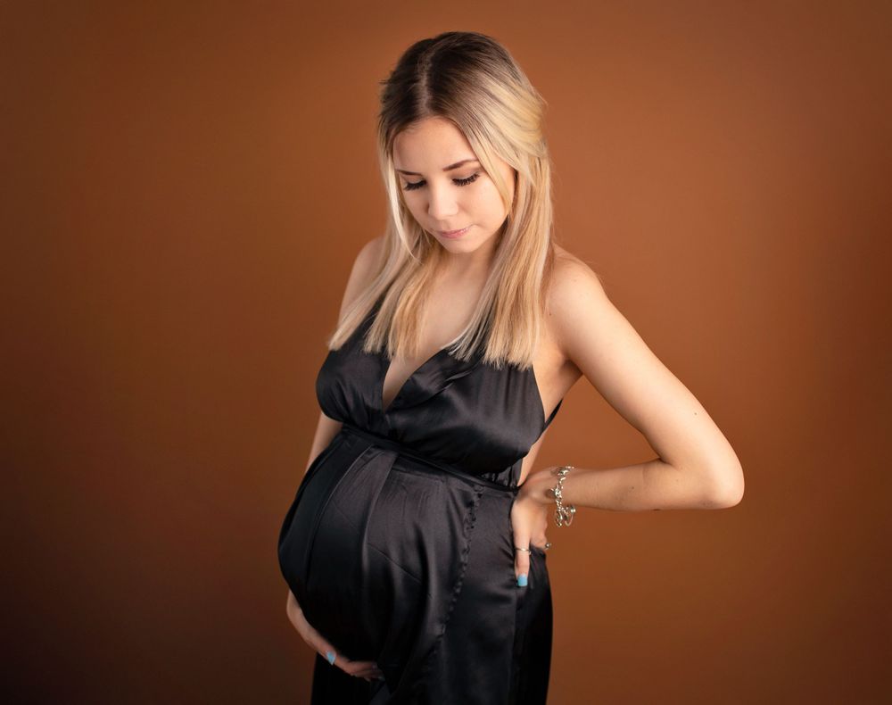 Mama in silk black maternity dress holding belly and looking at her belly in Alvin tx studioi