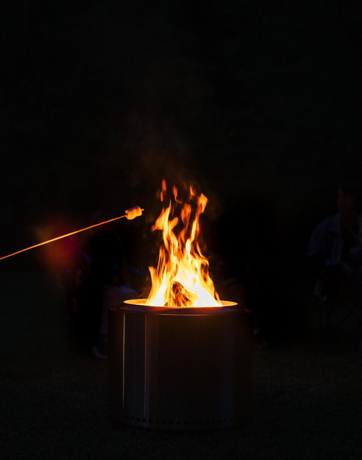 A sequence of fire burning in a dark container at night.