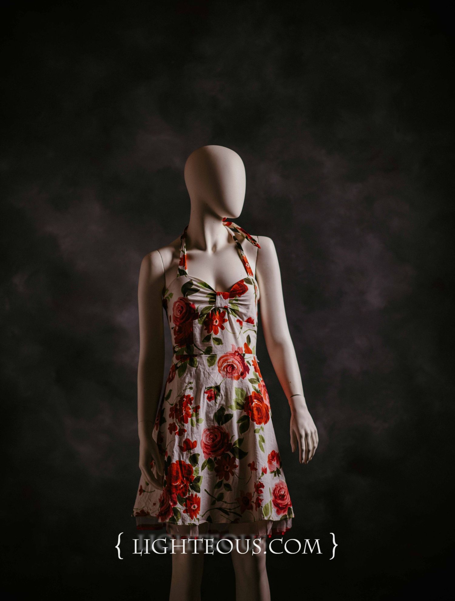 Artistic portrait showing floral dress against dark background in moody lighting.