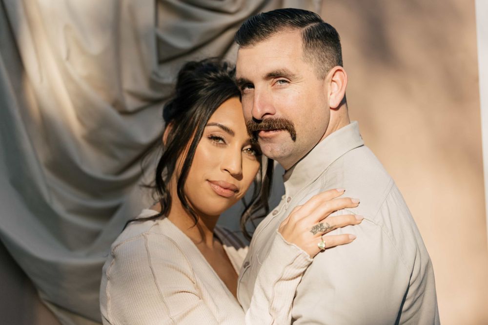 Romantic couple portrait with woman leaning on man's shoulder in warm natural light.