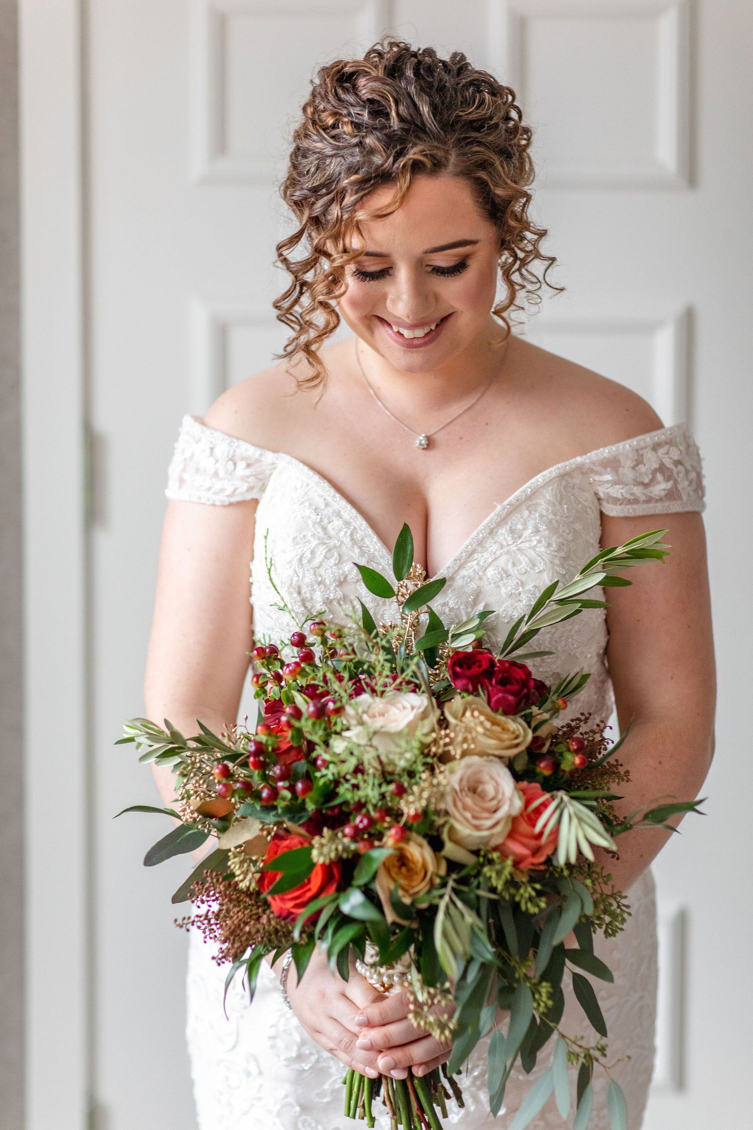 Elegant wedding bouquet featuring red and cream roses with mixed greenery.