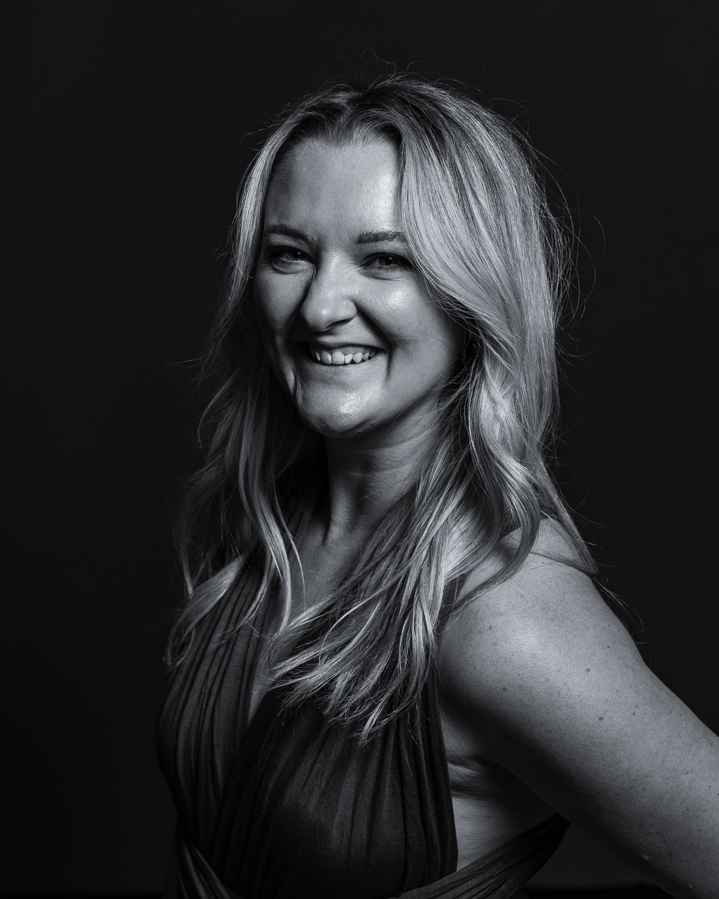 Black and white portrait showing joyful expression against dark background.