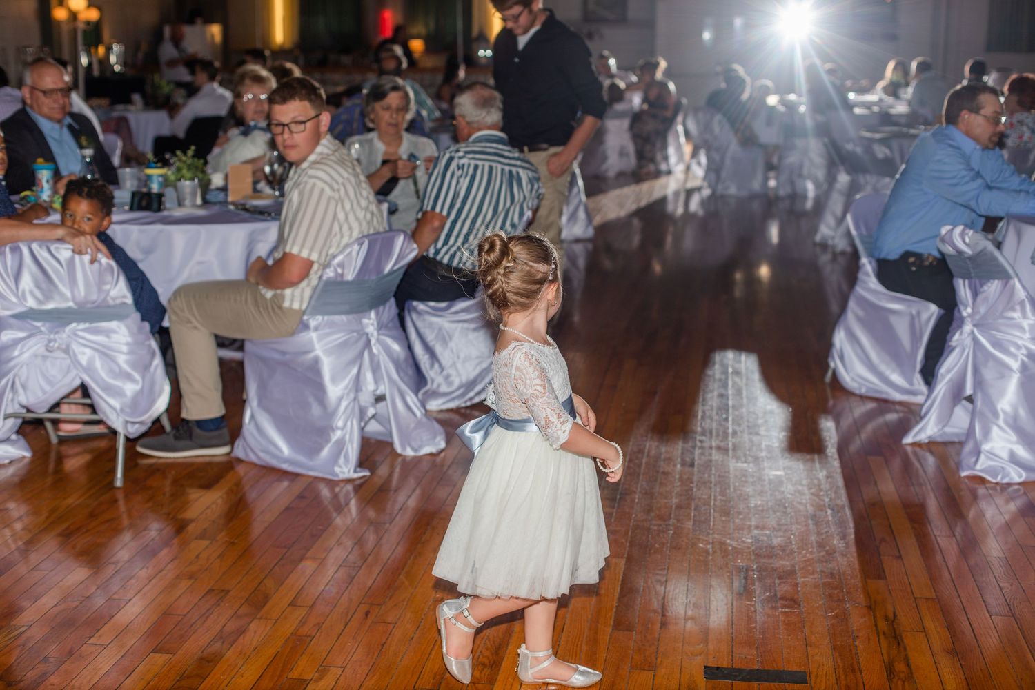 Wedding guests dancing and celebrating on wooden dance floor at reception.