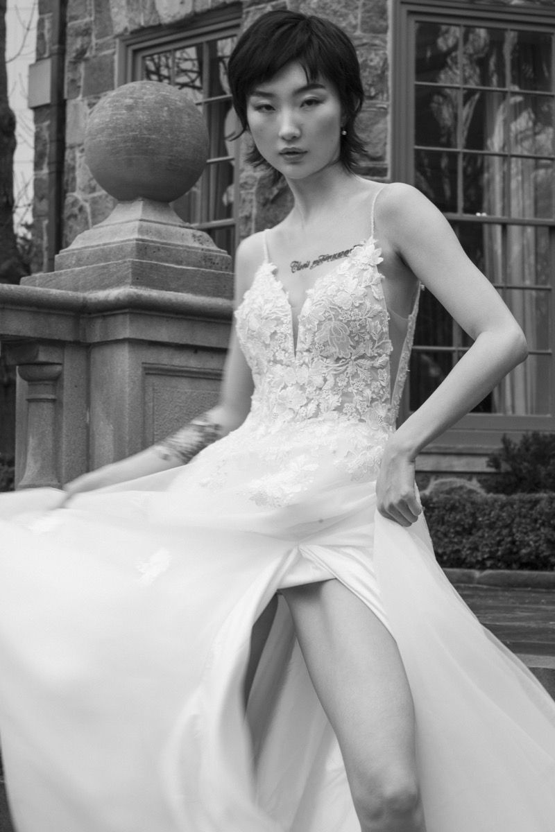 A bride in a white lace wedding dress poses outdoors, creating movement with the flowing skirt of her gown.