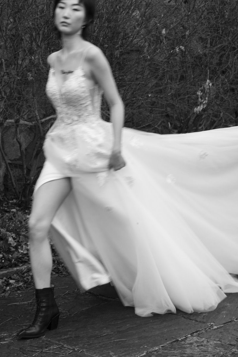 Black and white photo of a bride in a flowing wedding dress and boots creating dynamic movement.