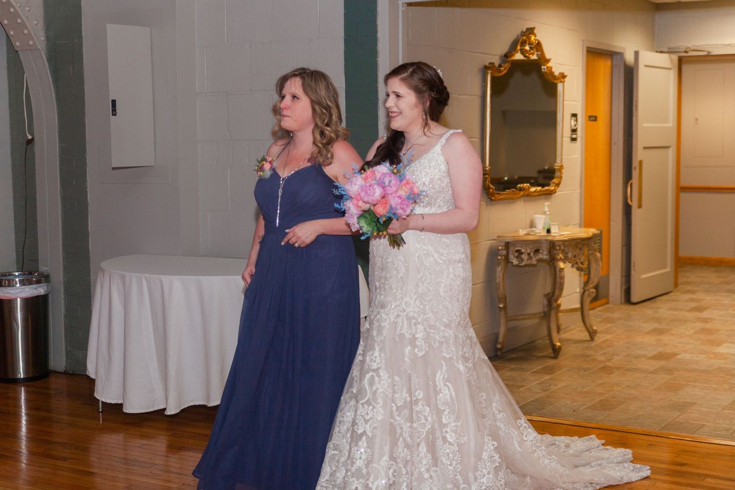 Wedding party members walking and posing in hallway during indoor celebration.