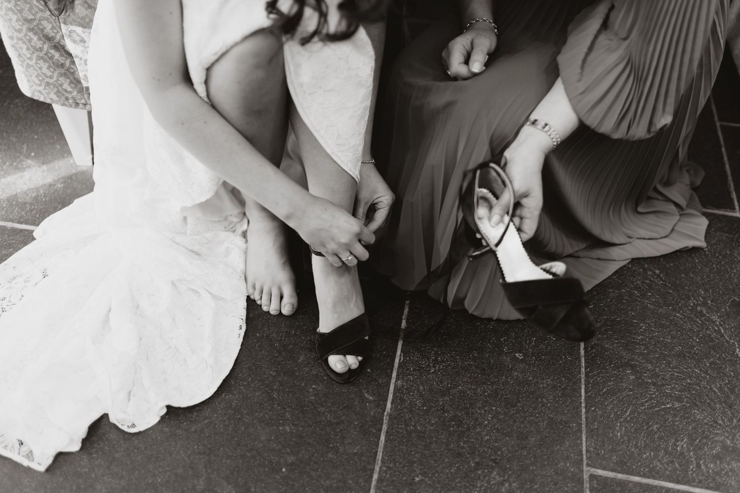 Bride putting on her shoes with the help of her mother on wedding morning
