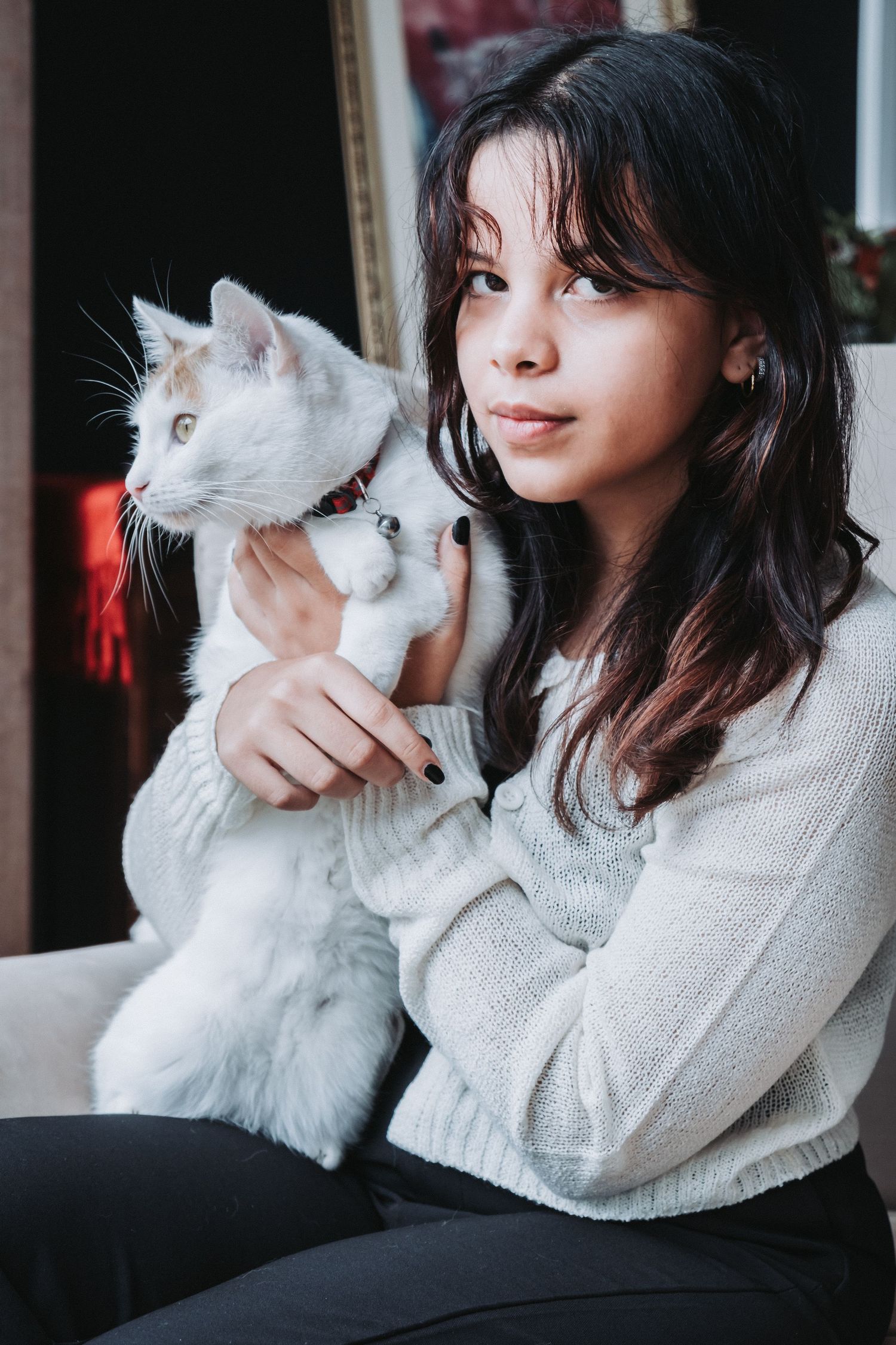 Woman cuddling with white cat on sofa in cozy indoor portrait.
