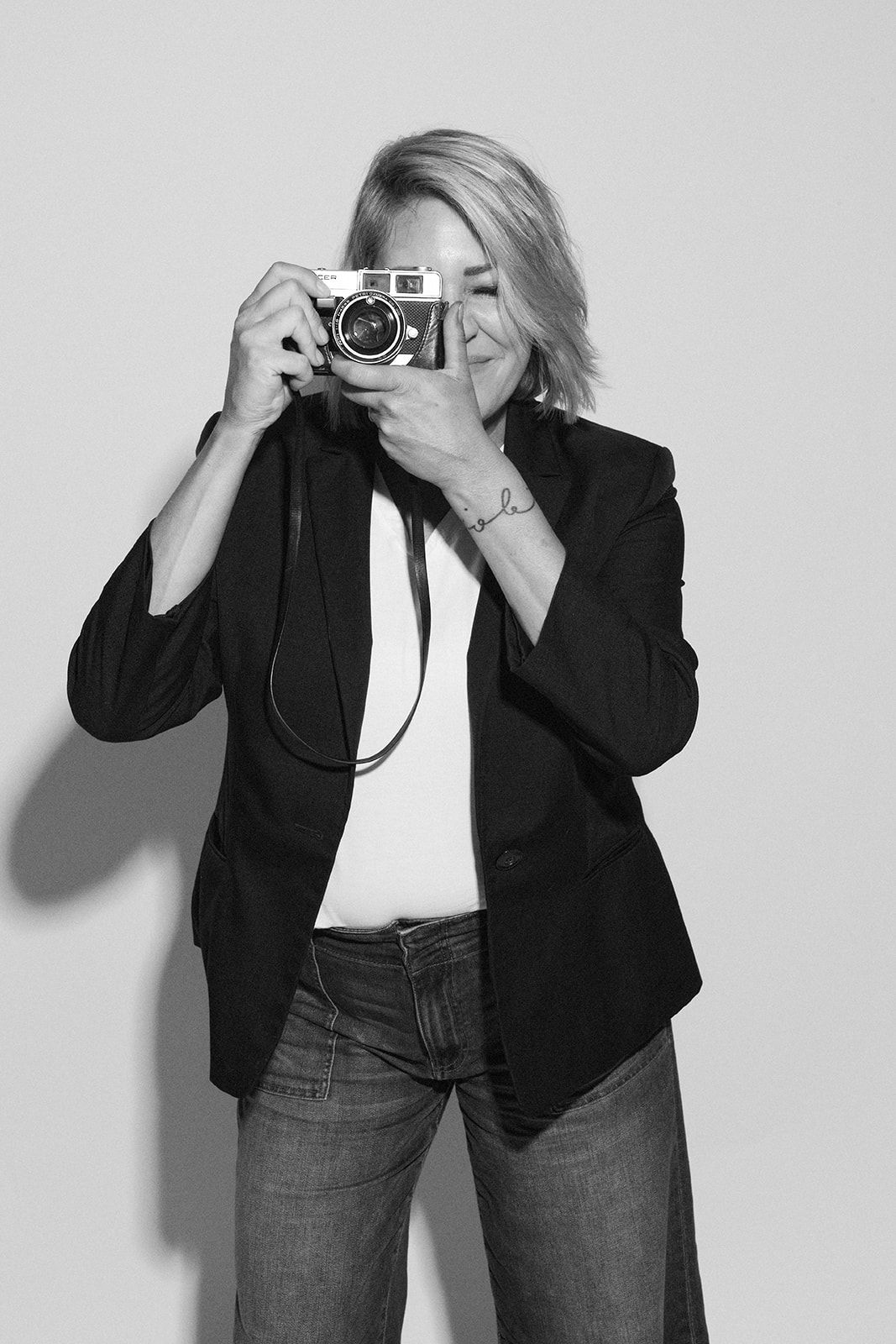 Series showing photographer taking pictures in black blazer and jeans against white background.