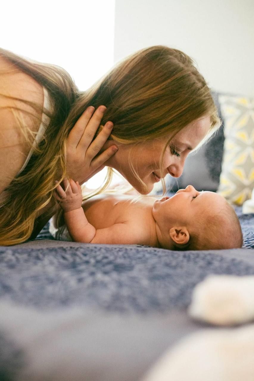 An intimate moment between parent and baby laying on blue bedding.