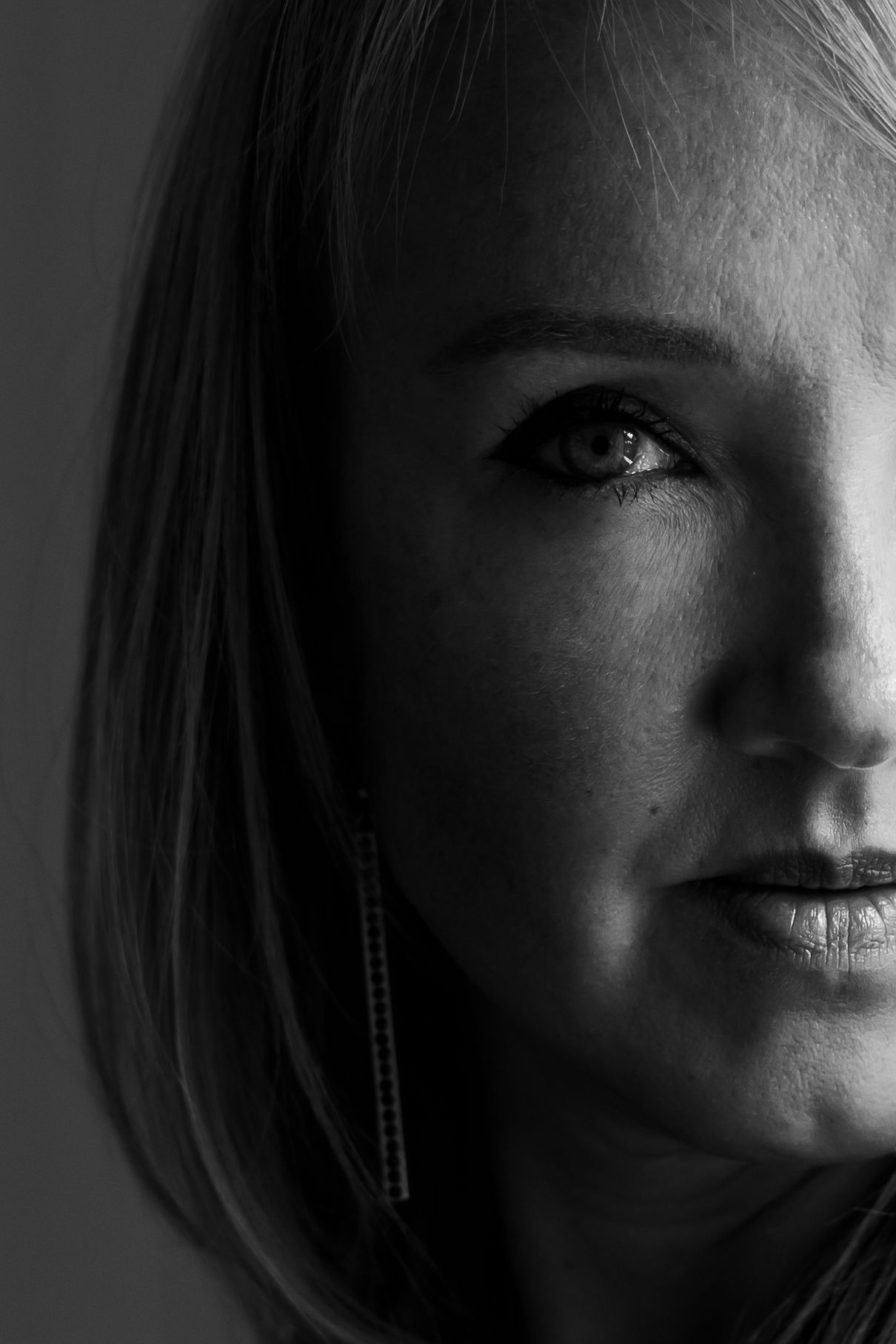 Dramatic black and white close-up portrait of a blonde woman with soft studio lighting.