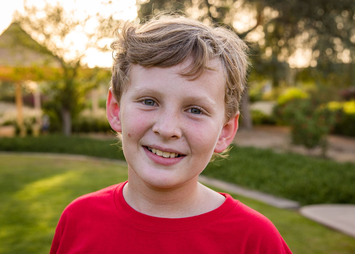 Boy in red top in park photoshoot - bright colour against green backdrop