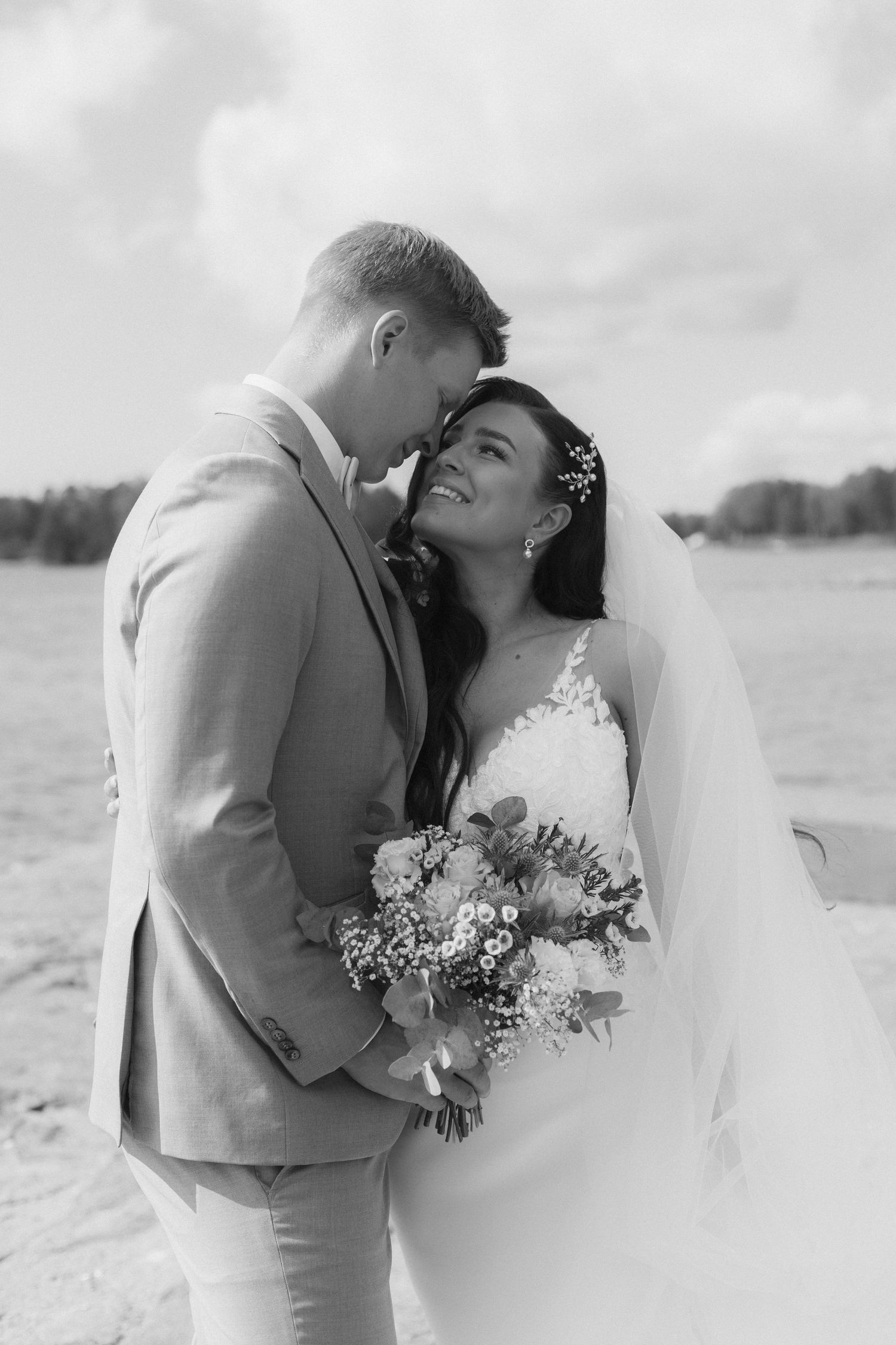 A beach wedding couple sharing a tender moment in black and white photography.